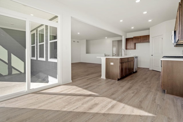 kitchen featuring a kitchen island with sink, sink, light hardwood / wood-style floors, and appliances with stainless steel finishes