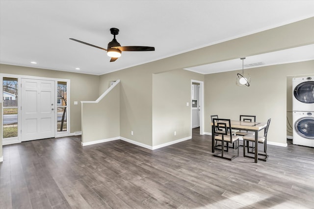 interior space with ceiling fan, wood-type flooring, ornamental molding, and stacked washer and clothes dryer