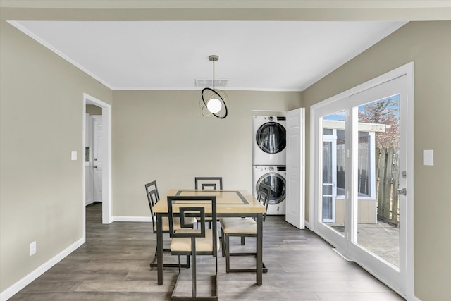 dining space with dark hardwood / wood-style floors, crown molding, and stacked washer and dryer