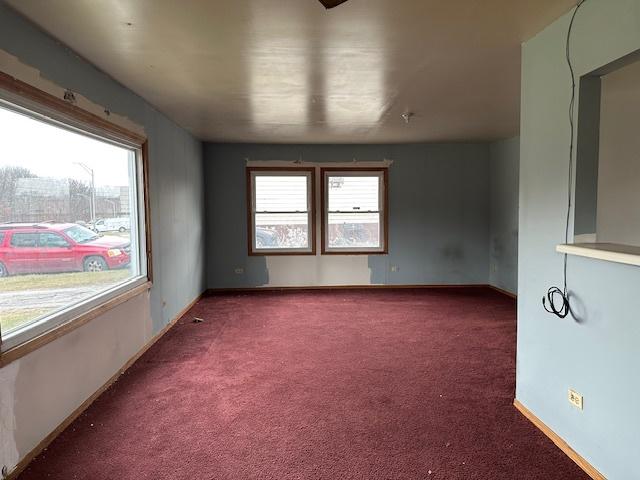 spare room featuring dark carpet and plenty of natural light