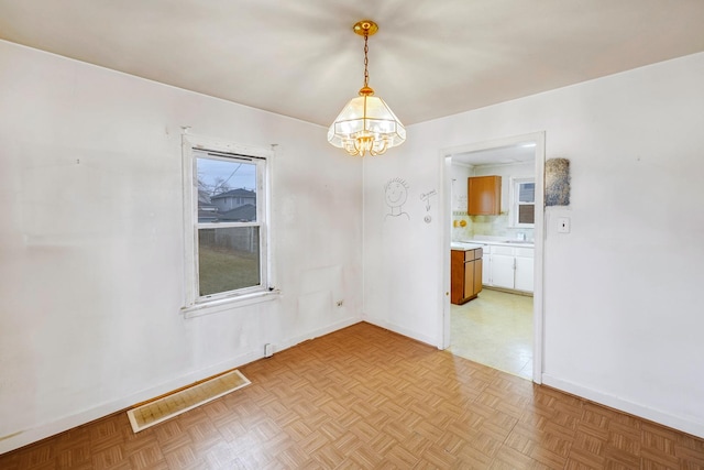 empty room featuring light parquet floors and a chandelier