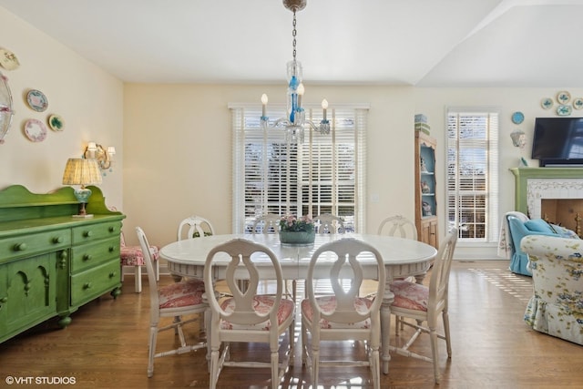 dining room featuring a tiled fireplace, wood-type flooring, and a chandelier