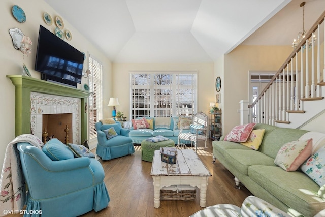 living room featuring a premium fireplace, a chandelier, lofted ceiling, and hardwood / wood-style flooring