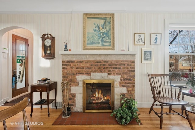 living area featuring hardwood / wood-style flooring, a fireplace, and ornamental molding