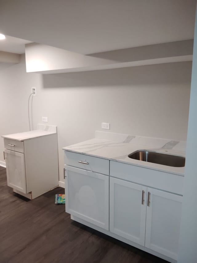 kitchen with white cabinets, light stone countertops, and dark wood-type flooring