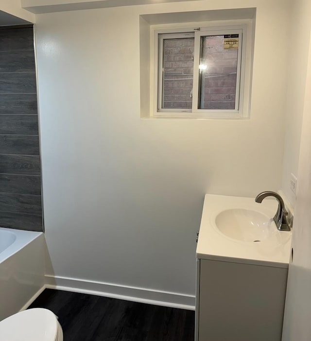 bathroom with hardwood / wood-style flooring, vanity, toilet, and a bathing tub