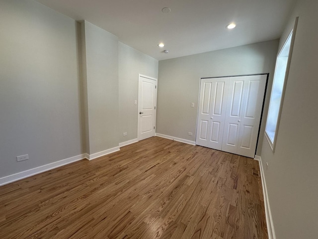 unfurnished bedroom with light wood-type flooring and a closet