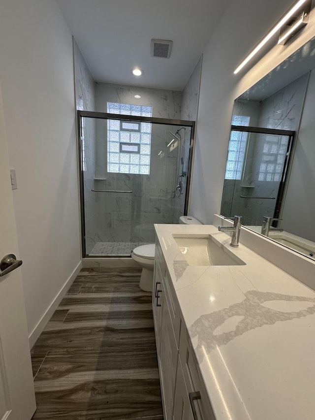 bathroom featuring vanity, toilet, and a shower with shower door