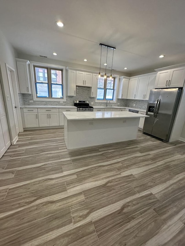 kitchen featuring hanging light fixtures, white cabinets, and stainless steel appliances