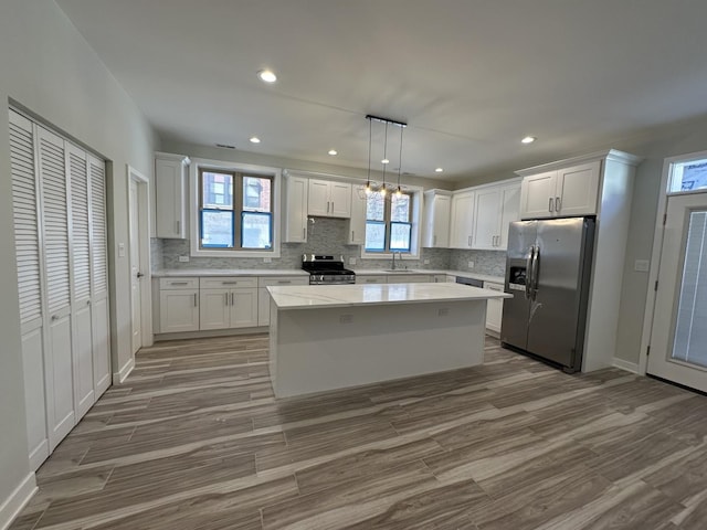 kitchen with a center island, stainless steel appliances, white cabinetry, and hanging light fixtures