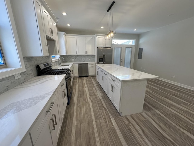 kitchen with hanging light fixtures, stainless steel appliances, a kitchen island, and white cabinetry