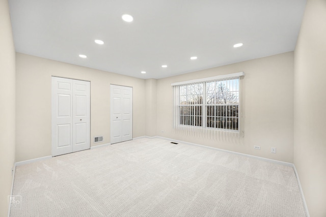 unfurnished room with carpet floors, baseboards, visible vents, and recessed lighting