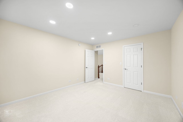 spare room featuring light colored carpet, visible vents, baseboards, and recessed lighting