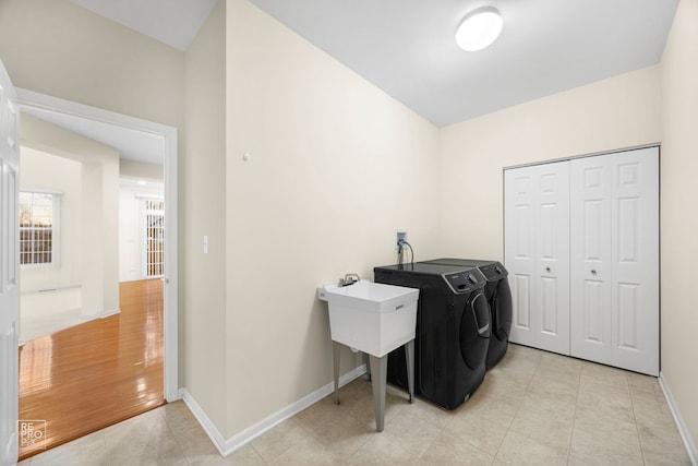 laundry area featuring laundry area, baseboards, washing machine and clothes dryer, and light tile patterned floors