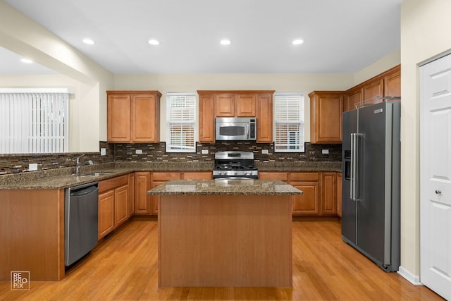 kitchen featuring light wood-type flooring, a wealth of natural light, stainless steel appliances, and a sink