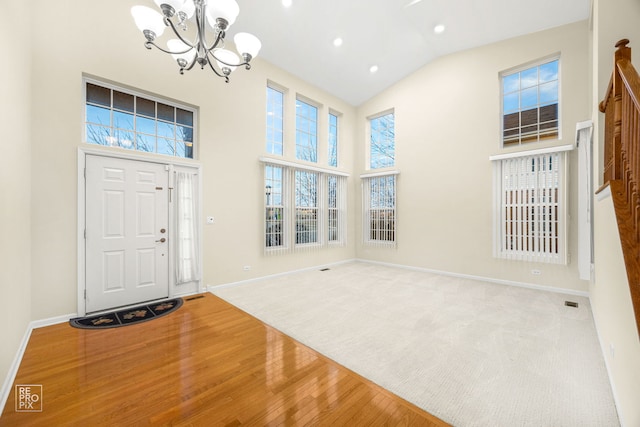 entrance foyer featuring a notable chandelier, recessed lighting, wood finished floors, high vaulted ceiling, and baseboards