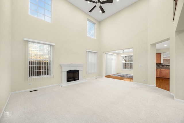 unfurnished living room with carpet floors, a fireplace with raised hearth, plenty of natural light, and baseboards