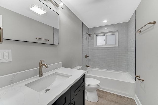 full bathroom with vanity, toilet, wood-type flooring, and tiled shower / bath