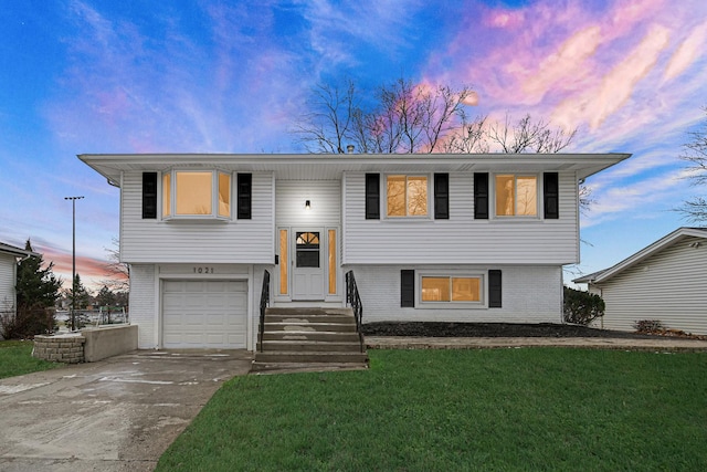 split foyer home featuring a garage and a lawn