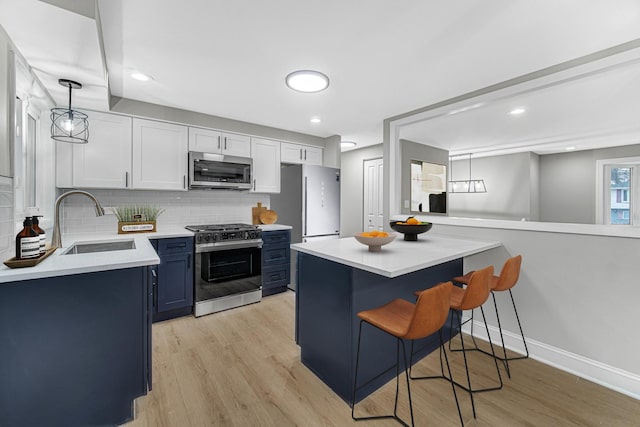 kitchen with a breakfast bar, blue cabinets, sink, white cabinetry, and stainless steel appliances