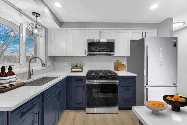 kitchen with blue cabinetry, appliances with stainless steel finishes, white cabinetry, and sink