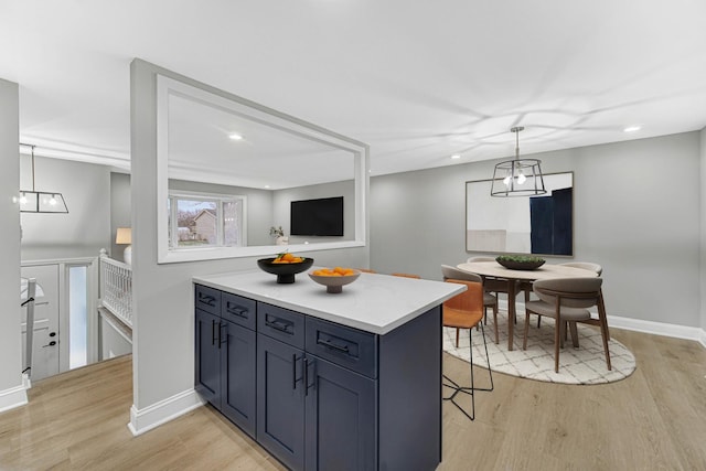 kitchen featuring a breakfast bar, decorative light fixtures, and light wood-type flooring