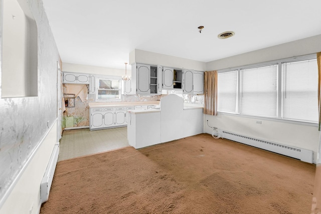 kitchen featuring baseboard heating, light colored carpet, and hanging light fixtures