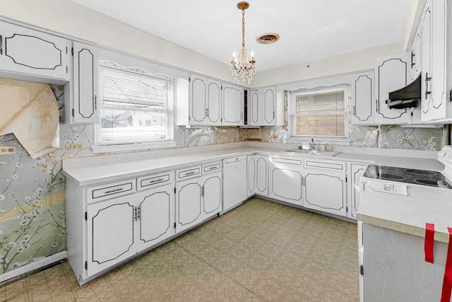 kitchen featuring decorative light fixtures, a wealth of natural light, white dishwasher, and sink