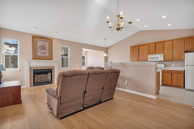 living room with a tile fireplace, vaulted ceiling, light hardwood / wood-style flooring, and a notable chandelier