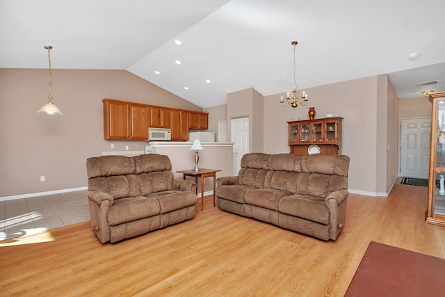 living room with a chandelier, light hardwood / wood-style floors, and lofted ceiling