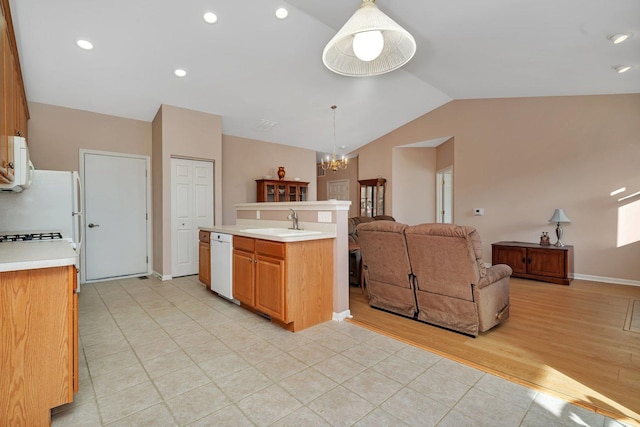 kitchen with pendant lighting, white appliances, sink, vaulted ceiling, and a notable chandelier