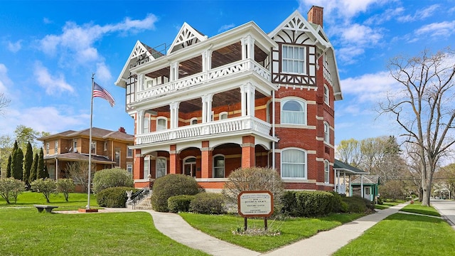 view of front facade featuring a balcony, a front lawn, and covered porch