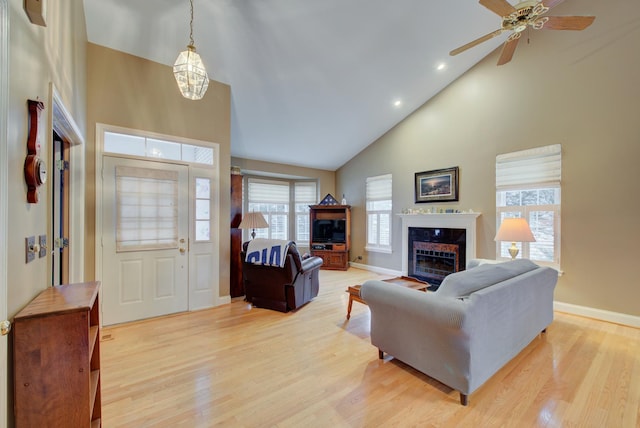 living room featuring a premium fireplace, high vaulted ceiling, ceiling fan, and light hardwood / wood-style floors