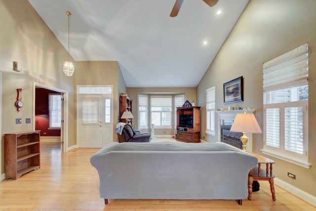 living room with ceiling fan, high vaulted ceiling, and light hardwood / wood-style flooring