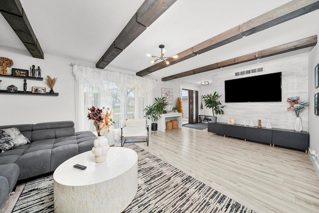 living room with a chandelier, beam ceiling, and light wood-type flooring