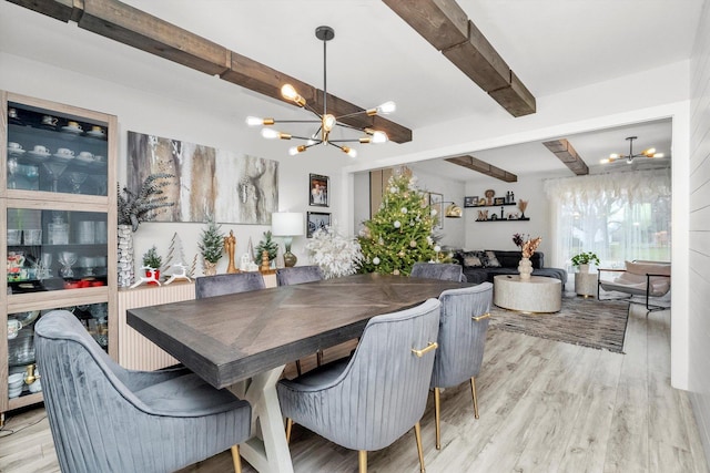 dining space with beam ceiling, a chandelier, and light wood-type flooring