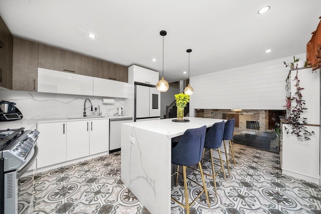 kitchen with white appliances, sink, decorative light fixtures, white cabinets, and a center island