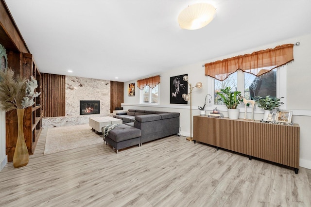 living room featuring a fireplace, radiator heating unit, a healthy amount of sunlight, and light wood-type flooring