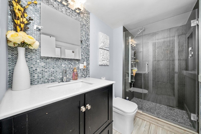 bathroom featuring vanity, backsplash, hardwood / wood-style flooring, toilet, and a shower with shower door