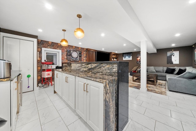 kitchen featuring white cabinets, dark stone countertops, and hanging light fixtures