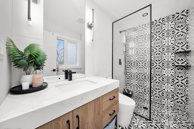 bathroom featuring a tile shower, vanity, and toilet