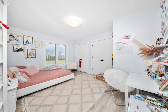 bedroom featuring light hardwood / wood-style flooring and multiple closets