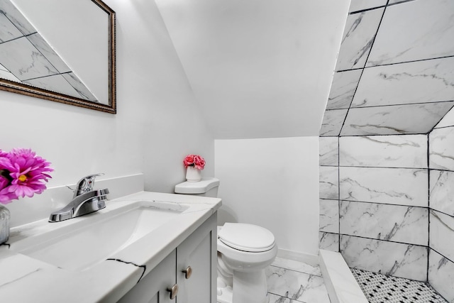 bathroom featuring a tile shower, vanity, and toilet