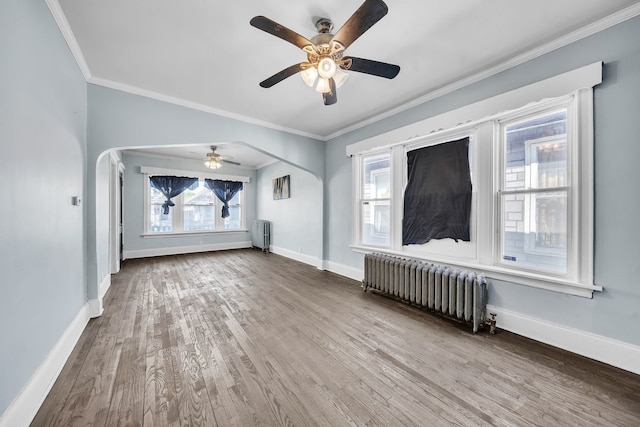 unfurnished living room with hardwood / wood-style flooring, ceiling fan, radiator heating unit, and crown molding