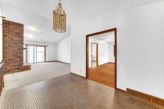 spare room featuring a textured ceiling, vaulted ceiling, and carpet