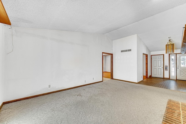 interior space featuring a textured ceiling, carpet floors, and vaulted ceiling