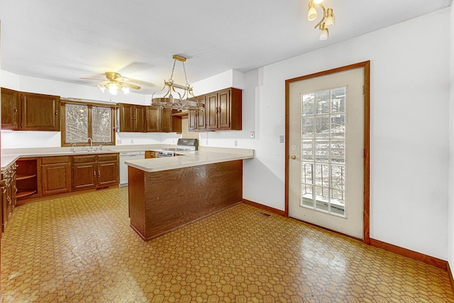 kitchen featuring kitchen peninsula, white dishwasher, pendant lighting, sink, and stove