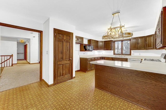 kitchen with sink, decorative light fixtures, stove, and kitchen peninsula