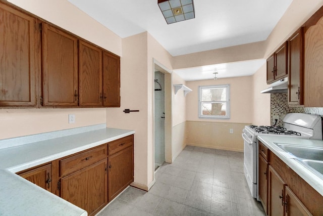 1009 Augusta Ave, Elgin, IL 60120 - kitchen with gas range gas stove, under cabinet range hood, brown cabinets, and light countertops