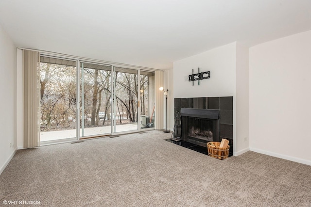 unfurnished living room with carpet, plenty of natural light, expansive windows, and a fireplace